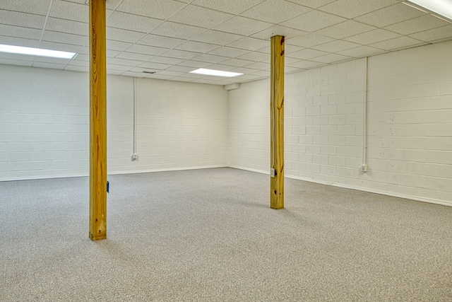 finished basement featuring a drop ceiling and concrete block wall