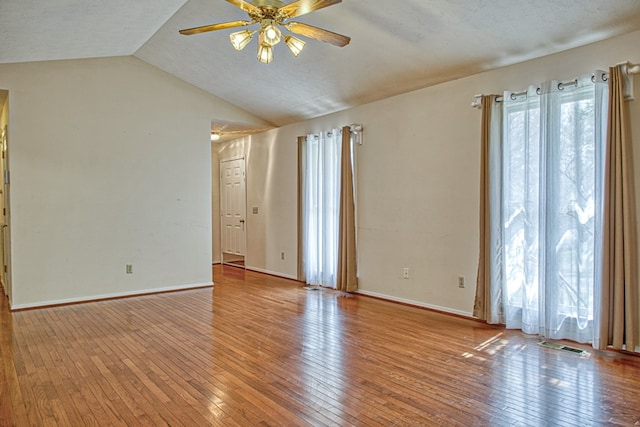 unfurnished room with hardwood / wood-style flooring, visible vents, lofted ceiling, and ceiling fan