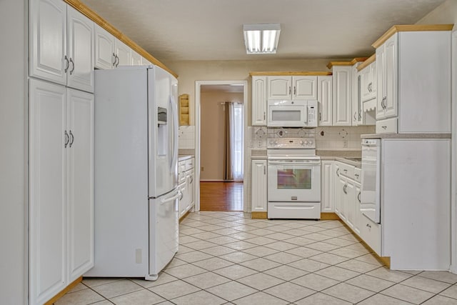 kitchen with tasteful backsplash, light tile patterned floors, white appliances, and light countertops