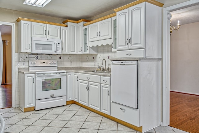 kitchen with a sink, white appliances, light countertops, and light tile patterned floors