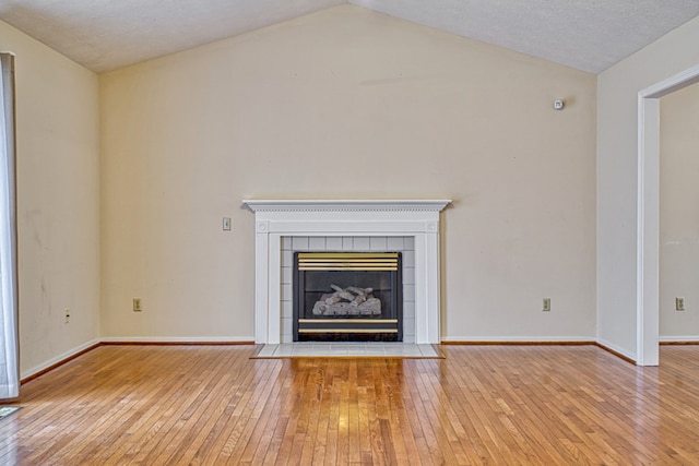 unfurnished living room with baseboards, lofted ceiling, light wood-style floors, and a fireplace