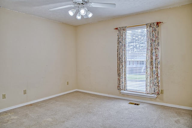 carpeted empty room with visible vents, baseboards, a textured ceiling, and ceiling fan