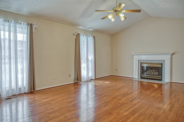 unfurnished living room featuring hardwood / wood-style floors, a ceiling fan, visible vents, lofted ceiling, and a tiled fireplace