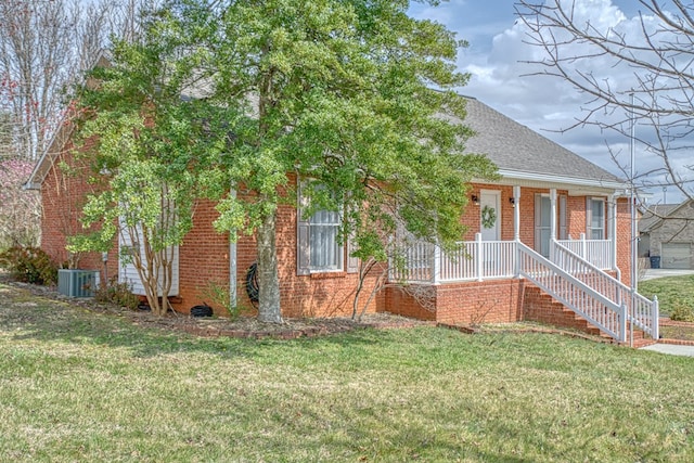 view of front of house featuring a front lawn, cooling unit, brick siding, and covered porch