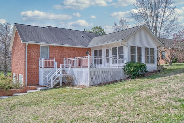 rear view of house featuring stairway, a lawn, a deck, and brick siding