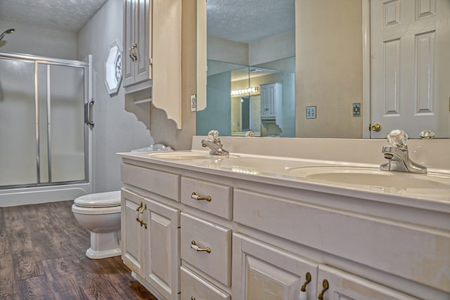 bathroom featuring a stall shower, wood finished floors, and a sink