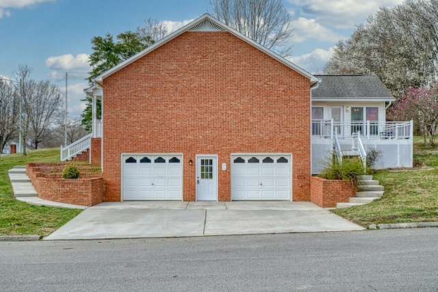 view of side of property with brick siding, stairway, driveway, and a garage