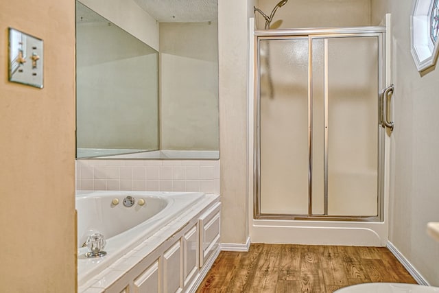 full bathroom with wood finished floors, a garden tub, a stall shower, and a textured ceiling