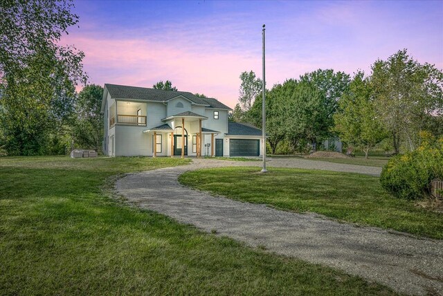 view of front of house featuring an attached garage, driveway, a front yard, and a balcony