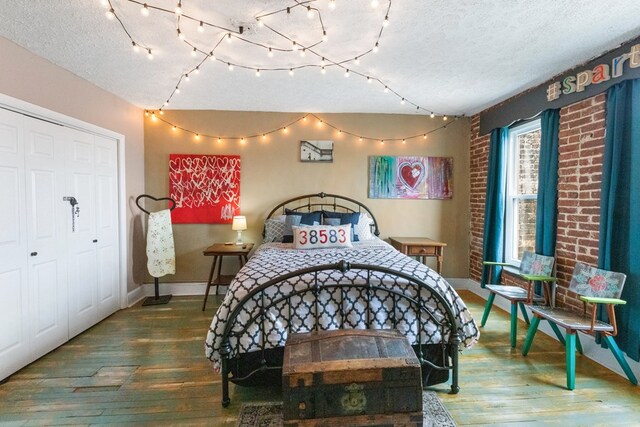 bedroom with a closet, a textured ceiling, baseboards, and wood finished floors