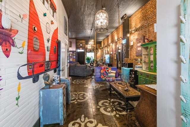 hall featuring brick wall and a notable chandelier