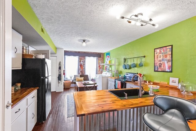 interior space with washer / dryer, visible vents, dark wood-style floors, a textured ceiling, and a sink