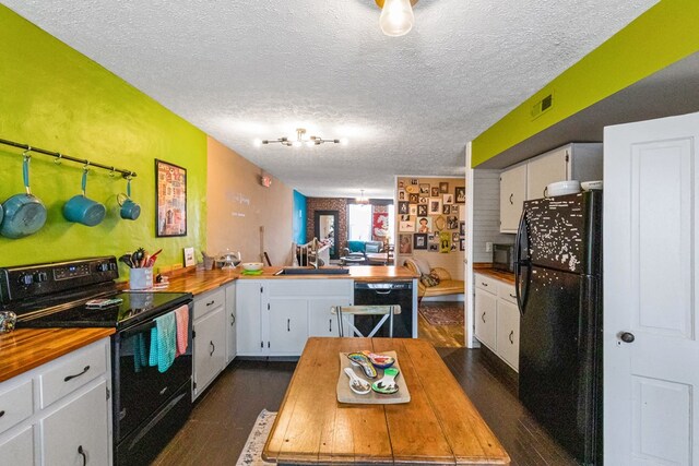 kitchen featuring butcher block countertops, white cabinetry, visible vents, and black appliances