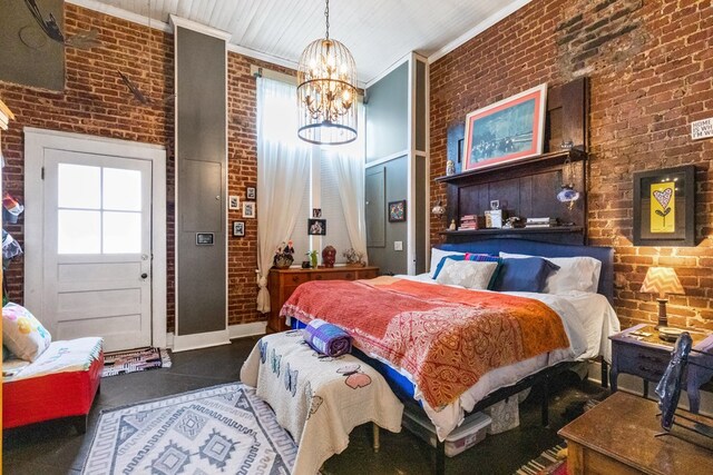 bedroom featuring a notable chandelier, crown molding, a towering ceiling, and brick wall