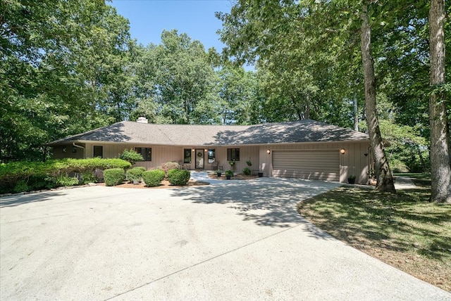 ranch-style home featuring a garage, driveway, and a chimney