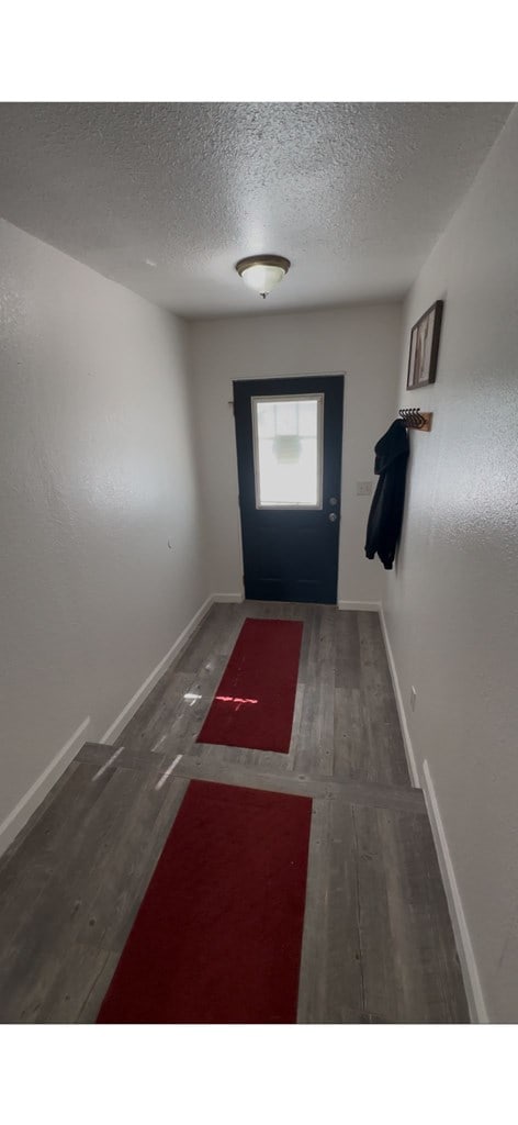 entryway featuring a textured ceiling, dark wood-type flooring, and baseboards