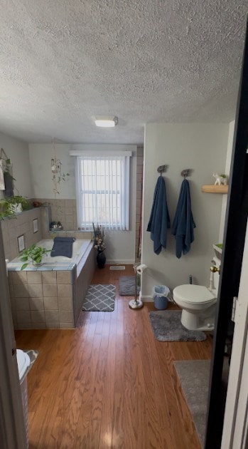 bathroom featuring a textured ceiling, toilet, and wood finished floors