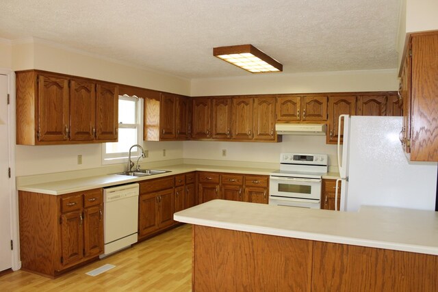 kitchen with under cabinet range hood, a peninsula, white appliances, a sink, and light countertops