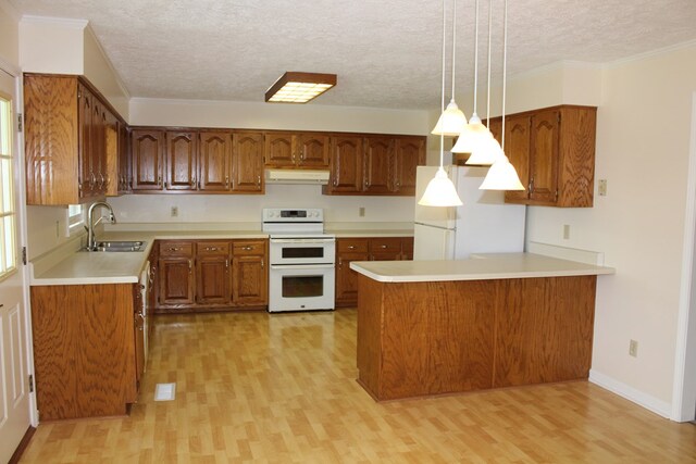 kitchen with under cabinet range hood, white appliances, a sink, light countertops, and decorative light fixtures