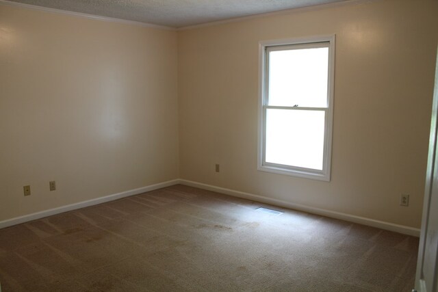 unfurnished room featuring carpet, crown molding, visible vents, a textured ceiling, and baseboards