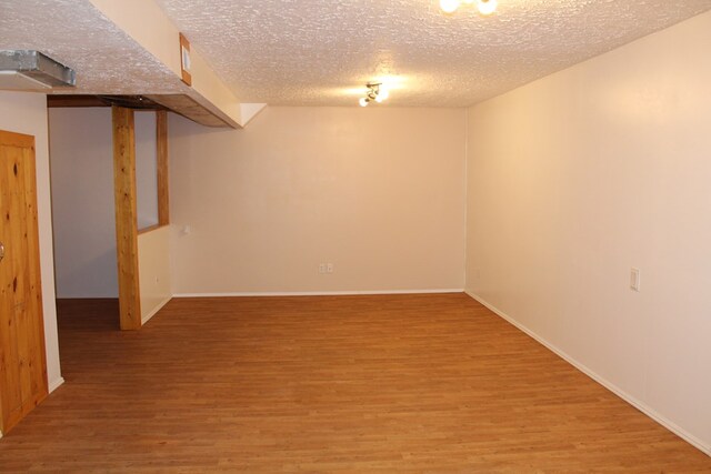 finished basement with a textured ceiling, baseboards, and wood finished floors