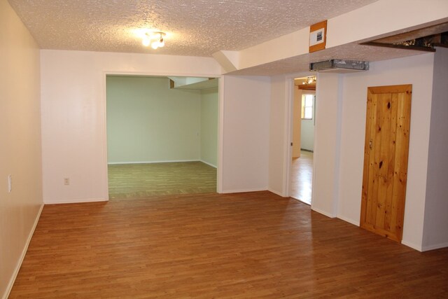 spare room featuring a textured ceiling, wood finished floors, visible vents, and baseboards