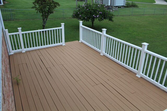 wooden terrace with a lawn and fence