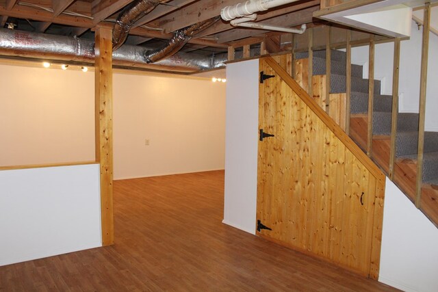 unfinished below grade area with stairway, wood finished floors, and baseboards