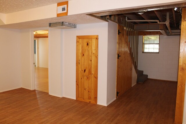 basement with stairway, a textured ceiling, visible vents, and wood finished floors