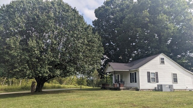 view of home's exterior featuring covered porch, metal roof, and a lawn