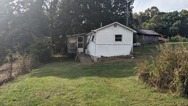 view of side of home featuring a yard and an outdoor structure