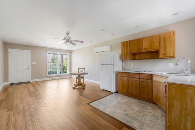 kitchen featuring baseboards, light wood-style flooring, freestanding refrigerator, light countertops, and a sink