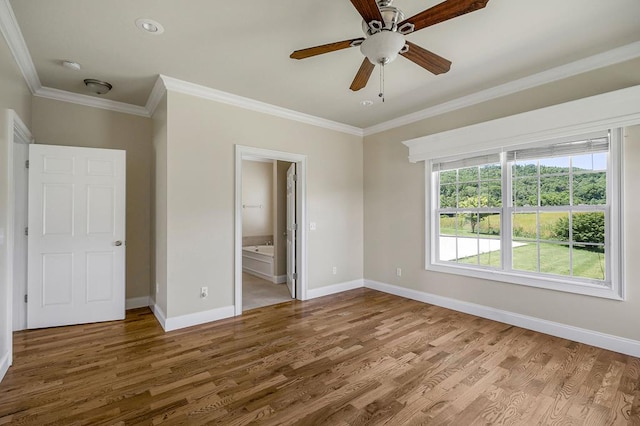 unfurnished bedroom featuring baseboards, ensuite bathroom, wood finished floors, and ornamental molding