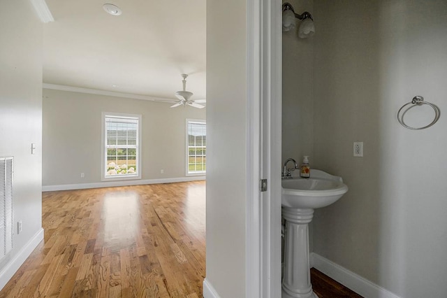 bathroom with ornamental molding, wood finished floors, a ceiling fan, and baseboards