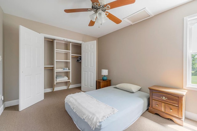 carpeted bedroom with attic access, baseboards, ceiling fan, and a closet