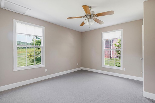 carpeted spare room featuring ceiling fan, attic access, and baseboards