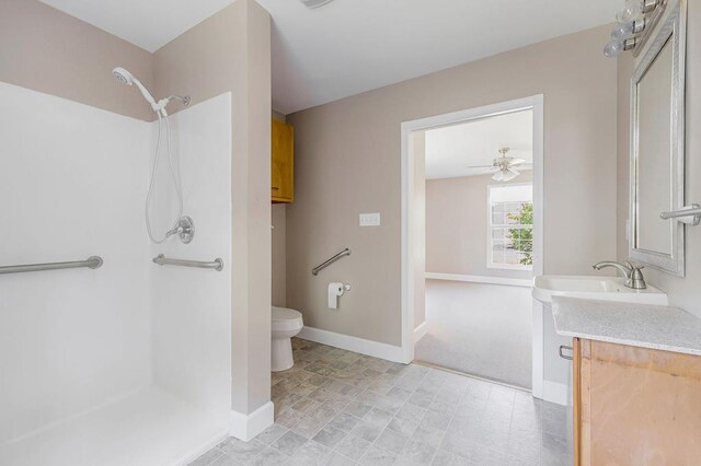 bathroom with toilet, baseboards, walk in shower, and vanity