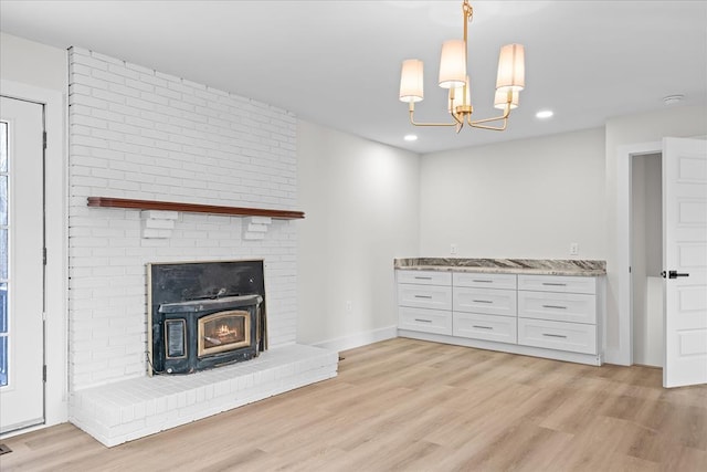 unfurnished living room featuring an inviting chandelier, recessed lighting, light wood-type flooring, and baseboards