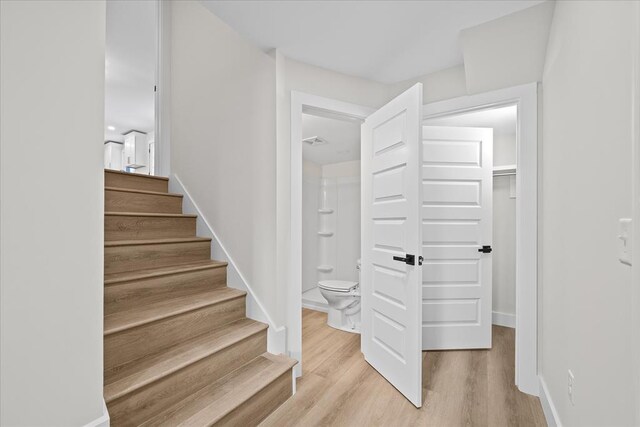 staircase featuring wood finished floors, visible vents, and baseboards