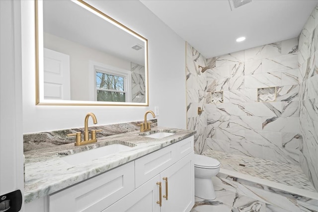 bathroom featuring double vanity, marble finish floor, toilet, and a sink