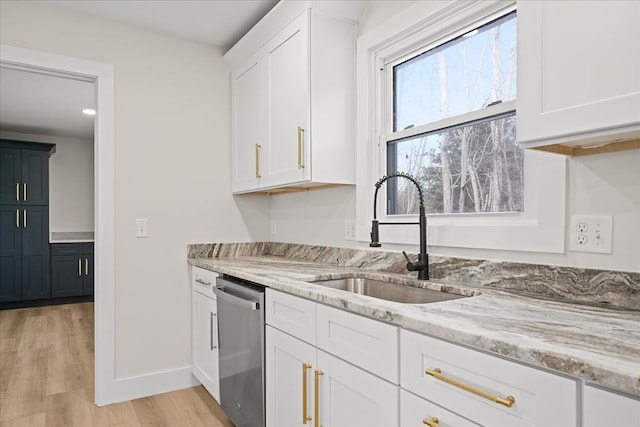 kitchen with light wood-type flooring, a sink, light stone counters, white cabinets, and dishwasher