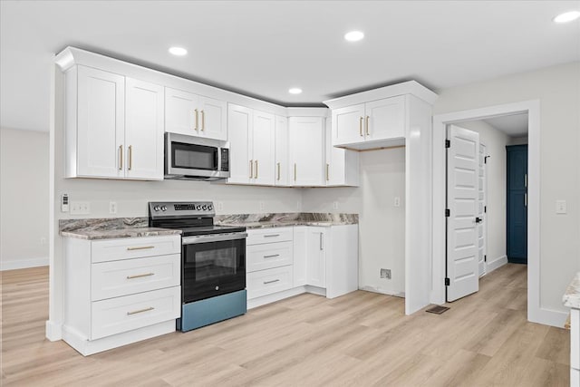 kitchen featuring light stone counters, appliances with stainless steel finishes, and white cabinetry