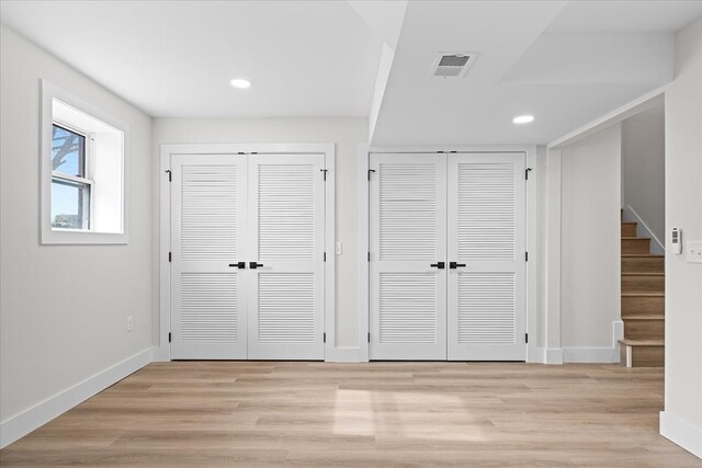 unfurnished bedroom featuring visible vents, baseboards, multiple closets, light wood-type flooring, and recessed lighting