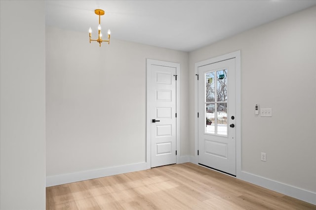 foyer entrance featuring light wood-type flooring, baseboards, and a notable chandelier