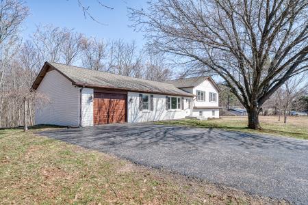 split level home with aphalt driveway, a garage, and a front lawn