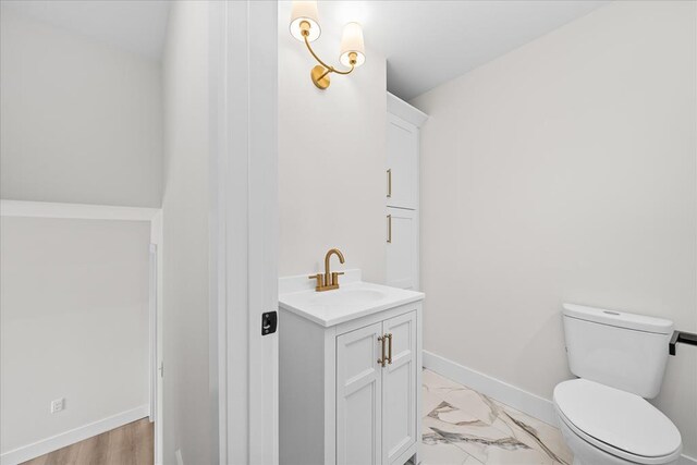 bathroom featuring baseboards, toilet, marble finish floor, and vanity