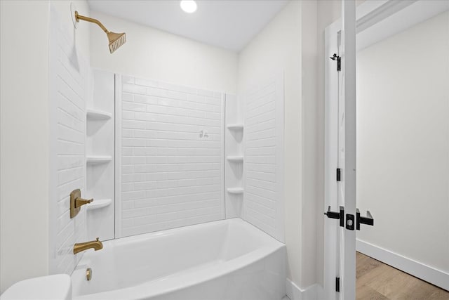 bathroom featuring shower / washtub combination, toilet, baseboards, and wood finished floors