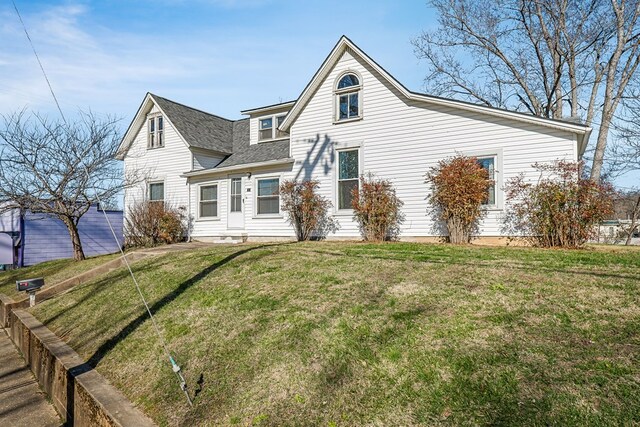 view of front of house with a front lawn and roof with shingles