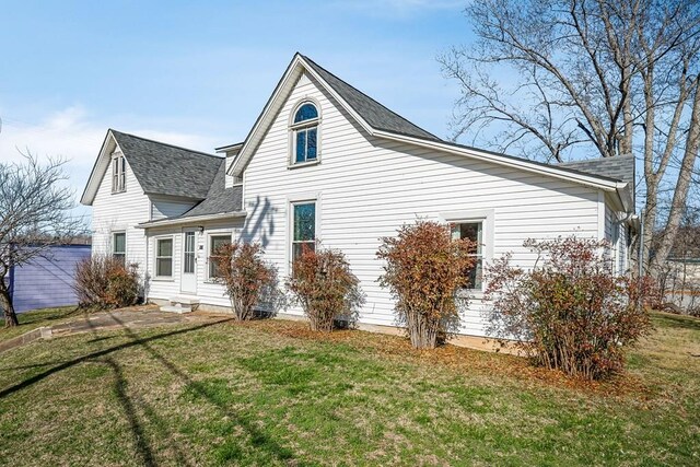 back of property with entry steps, a yard, and roof with shingles