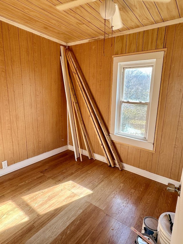 spare room with wood ceiling, wooden walls, wood finished floors, and baseboards